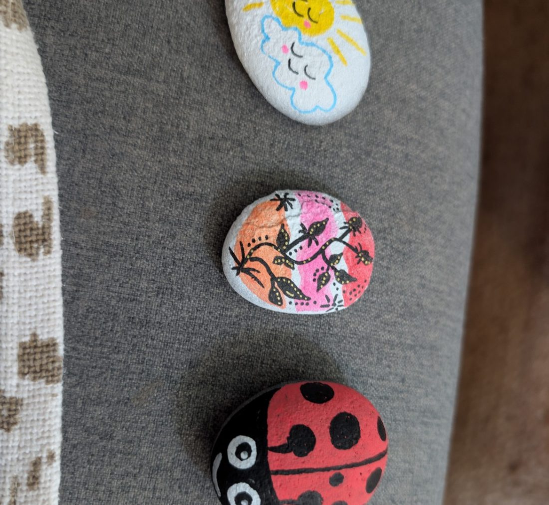 Galets peints par des enfants : un soleil, une coccinelle et un motif fleuri